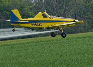 Yellow plane spraying crops in the field
